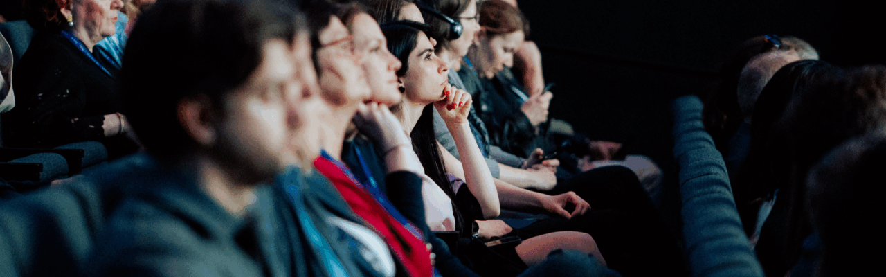 What It Takes to Get Meetings & Event Planning Right for 2026 8 People listening carefully in a conference.